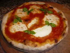 Pizza margherita med tomatsauce, mozzarella i pletter og friske basilikumblade