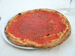 Pizza med kun tomatsauce og oregano, uden ost, på en hvid tallerken