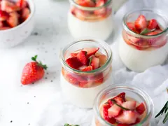 Små glas med hvid panna cotta og hakkede jordbær