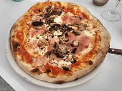 Pizza med skinke og skiver af mørke champignon på tomat og ost